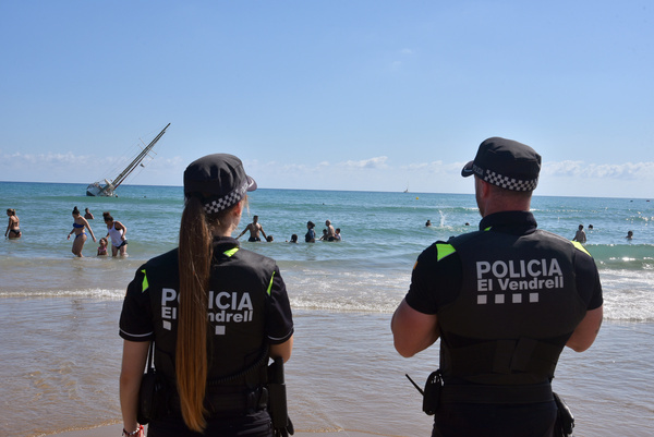 Two official agents of the Local Police of Vendrell warn people to leave the beach due to an accident by a sailboat that has been stranded in the sand of Coma-ruga beach. A sailboat has been stranded at the entrance to the port of Playa Coma-ruga in Vendrell. The Local Police of Vendrell has appeared in the place to guarantee the security of the environment.
For reasons that are being investigated, the ship has been stranded in the sand and has heeled, preventing it from continuing to sail.