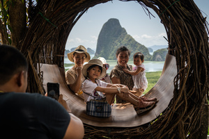 A family takes a photo together in front of Phang Nga Bay in Phuket.