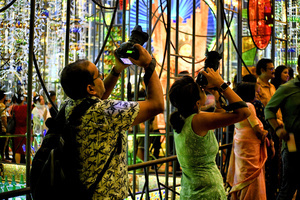 People take photos on their cameras in front of the entrance of a Pandal (Temporary place for Worship) made for Durgapuja. The city of Kolkata celebrates the largest festival of Bengali, Durga puja. Durga is a description of the power of the goddess in Hindu Mythology. UNESCO (The United Nations Educational, Scientific and Cultural Organization) in 2021 included Durga puja in the Representative list of the intangible cultural heritage of Humanity.