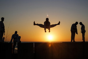 A Palestinian youth shows his skills as he practices taekwondo on the Mediterranean beach during sunset in Khan Yunis, southern Gaza Strip. The "Funoon" taekwondo team trains taekwondo at the Mediterranean beach at sunset, as part of a training program organized by the trainers in the team, as they allocate a day of training on the seashore of Khan Yunis, southern Gaza Strip.