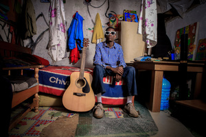 An 18-Year-Old artist Anthony Bwire poses in his living room in his room in the Kibera Slum. The young Kenyan youths are driven into a competency of having their own homes away from their parents where they, most importantly, learn to tackle life through different challenges. The competition to have the best-decorated rooms filled with different designer outfits is one way of avoiding daily difficulties such as drug abuse, teenage pregnancies, early marriages, and negative judgments from locals. To most young youths having a home is the start of a new life, and it comes with many responsibilities. Unauthorized housing is the most lucrative investment in Kenya today. Therefore for one to have a house with landlords renting rooms to let at Ksh 1,500 ($ 12) to Ksh 5000 ($ 40) a month, that is almost too hard to pay for most youths with low-income jobs and therefore needs an extra effort to raise their sources of income.