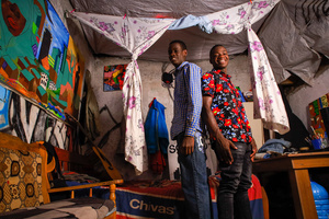 Nineteen-year-old boys, Anthony Bwire (L) and Saviour Omondi (R) pose in their living room which also acts as their art room in the Kibera Slum. The young Kenyan youths are driven into a competency of having their own homes away from their parents where they, most importantly, learn to tackle life through different challenges. The competition to have the best-decorated rooms filled with different designer outfits is one way of avoiding daily difficulties such as drug abuse, teenage pregnancies, early marriages, and negative judgments from locals. To most young youths having a home is the start of a new life, and it comes with many responsibilities. Unauthorized housing is the most lucrative investment in Kenya today. Therefore for one to have a house with landlords renting rooms to let at Ksh 1,500 ($ 12) to Ksh 5000 ($ 40) a month, that is almost too hard to pay for most youths with low-income jobs and therefore needs an extra effort to raise their sources of income.