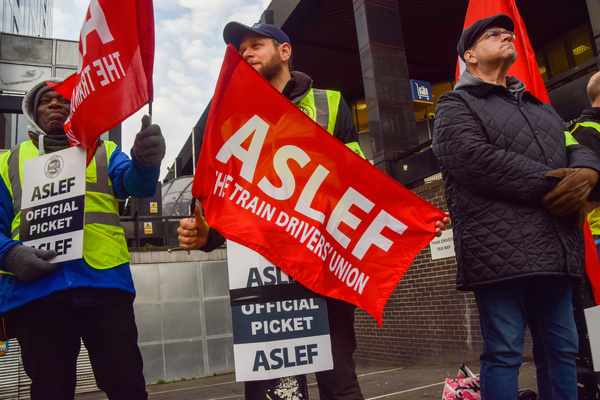 ASLEF (Associated Society of Locomotive Engineers and Firemen) members hold union flags at the picket outside Euston Station as train drivers continue their strike across the UK.