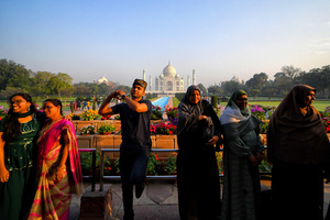 Tourists pose for photos in front of the Taj Mahal in Agra. The Taj Mahal is a mausoleum located in the right bank of the river Yamuna - Agra, India, built by Mughal Emperor Shah Jahan in memory of his favorite wife, Mumtaz. The Taj Mahal is considered the finest example of Mughal architecture, a style that combines elements from Persian, Oman, Indian, and Islamic architectural styles. The Taj Mahal is in the list of modern Seven Wonders of the World and It has also been a protected UNESCO World Heritage Site since 1983.