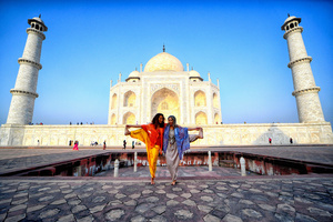Foreign Tourists seen posing in different Yoga (Physical exercise) styles in front of the Taj Mahal in Agra. The Taj Mahal is a mausoleum located in the right bank of the river Yamuna - Agra, India, built by Mughal Emperor Shah Jahan in memory of his favorite wife, Mumtaz. The Taj Mahal is considered the finest example of Mughal architecture, a style that combines elements from Persian, Oman, Indian, and Islamic architectural styles. The Taj Mahal is in the list of modern Seven Wonders of the World and It has also been a protected UNESCO World Heritage Site since 1983.