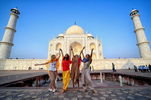 Foreign Tourists seen posing in different styles in front of the Taj Mahal in Agra. The Taj Mahal is a mausoleum located in the right bank of the river Yamuna - Agra, India, built by Mughal Emperor Shah Jahan in memory of his favorite wife, Mumtaz. The Taj Mahal is considered the finest example of Mughal architecture, a style that combines elements from Persian, Oman, Indian, and Islamic architectural styles. The Taj Mahal is in the list of modern Seven Wonders of the World and It has also been a protected UNESCO World Heritage Site since 1983.