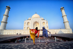 Foreign Tourists seen posing in different Yoga (Physical exercise) styles in front of the Taj Mahal in Agra. The Taj Mahal is a mausoleum located in the right bank of the river Yamuna - Agra, India, built by Mughal Emperor Shah Jahan in memory of his favorite wife, Mumtaz. The Taj Mahal is considered the finest example of Mughal architecture, a style that combines elements from Persian, Oman, Indian, and Islamic architectural styles. The Taj Mahal is in the list of modern Seven Wonders of the World and It has also been a protected UNESCO World Heritage Site since 1983.