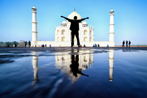 A tourist poses for a photo in front of the Taj Mahal. The Taj Mahal is a mausoleum located in the right bank of the river Yamuna - Agra, India, built by Mughal Emperor Shah Jahan in memory of his favorite wife, Mumtaz. The Taj Mahal is considered the finest example of Mughal architecture, a style that combines elements from Persian, Oman, Indian, and Islamic architectural styles. The Taj Mahal is in the list of modern Seven Wonders of the World and It has also been a protected UNESCO World Heritage Site since 1983.