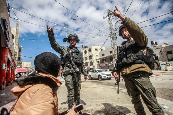 Israeli soldiers try to chase away a Palestinian lady in the middle of the town of Hawara, after a shooting attack on a Jewish settler's car in the town, south of Nablus, in the occupied West Bank. The Israeli army closed all commercial shops in the town of Hawara and deployed its forces throughout.