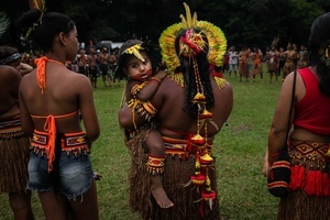 A woman wearing ornaments made out of natural elements carries a child during the celebrations of the Indigenous People’s Day, at the Aldeia Katurãma.