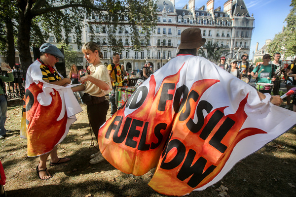 A protester wears a cape saying ‘End Fossil Fuels now’ as climate demonstrators gather. This weekend will see millions of people around the world taking to the streets to demand a rapid, just, and equitable end to fossil fuels.
