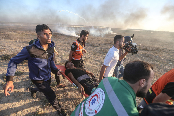 Medical workers carry an injured Palestinian during the demonstration. The Palestinian factions organized demonstrations along the border fence between the Gaza Strip and Israel against Israeli violations in Jerusalem and Al-Aqsa Mosque, coinciding with the Israeli religious holidays.