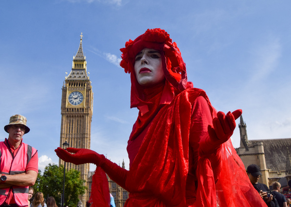 A member of the Red Rebel Brigade wearing a costume performs during the protest in Parliament Square. Extinction Rebellion activists marched through Westminster in protest against new fossil fuels.