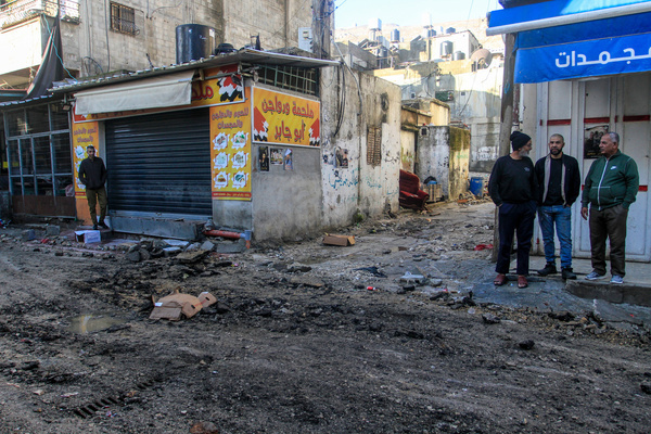 Palestinians seen on a damaged street in Balata refugee camp in the West Bank. The aftermath of an Israeli raid at the Balata refugee camp in the West Bank, as violence escalates in the occupied Palestinian territory amid Israel's war against Hamas in Gaza.