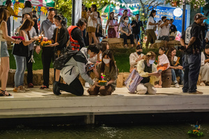 A young couple is seen with their krathong on the bank of the lake during the Magical Loy Krathong Festival at Jodd Fairs Dan Neramit in Bangkok. Loy Krathong, Thailand's Festival of Lights, is celebrated annually across Thailand and nearby regions. During this festival, people float decorated baskets made of banana leaves, incense sticks, and candles on rivers, canals, or ponds. They make wishes as they release these floating offerings.