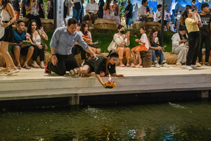 A man is seen holding his wife while she is putting her krathong on the lake during the Magical Loy Krathong Festival at Jodd Fairs Dan Neramit in Bangkok. Loy Krathong, Thailand's Festival of Lights, is celebrated annually across Thailand and nearby regions. During this festival, people float decorated baskets made of banana leaves, incense sticks, and candles on rivers, canals, or ponds. They make wishes as they release these baskets.