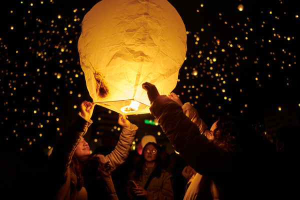 Two people hold a lantern while waiting for it to fly. The Pamplona City Council has distributed 4,000 free lanterns to the citizens on the occasion of the day of San Saturnino, patron saint of the city.