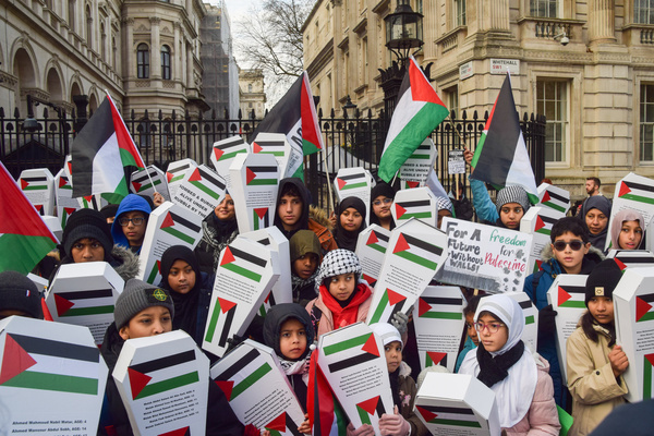 Children hold small cardboard 'coffins' representing over 6000 Palestinian children reportedly killed by Israeli forces or missing in Gaza and Palestinian flags during the demonstration. Pro-Palestine parents and children gathered outside Downing Street calling for a permanent ceasefire as Israel pauses the fighting with Hamas.
