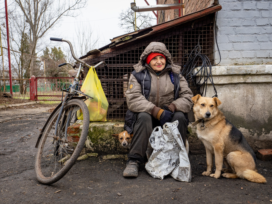 Saraja with her dogs waits for humanitarian aid. Toretsk is a mining town in the eastern Ukraine, turned into scratch by shelling. Russian positions are just few kilometres away. There is no electricity and water, people fetch water from public wells and can only heat their apartments by wooden stoves.There is no transport and work taking place in the area.