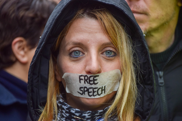 A supporter of Julian Assange with tape over her mouth with the words "free speech" stands outside the High Court on the second day of the WikiLeaks founder's extradition hearing.