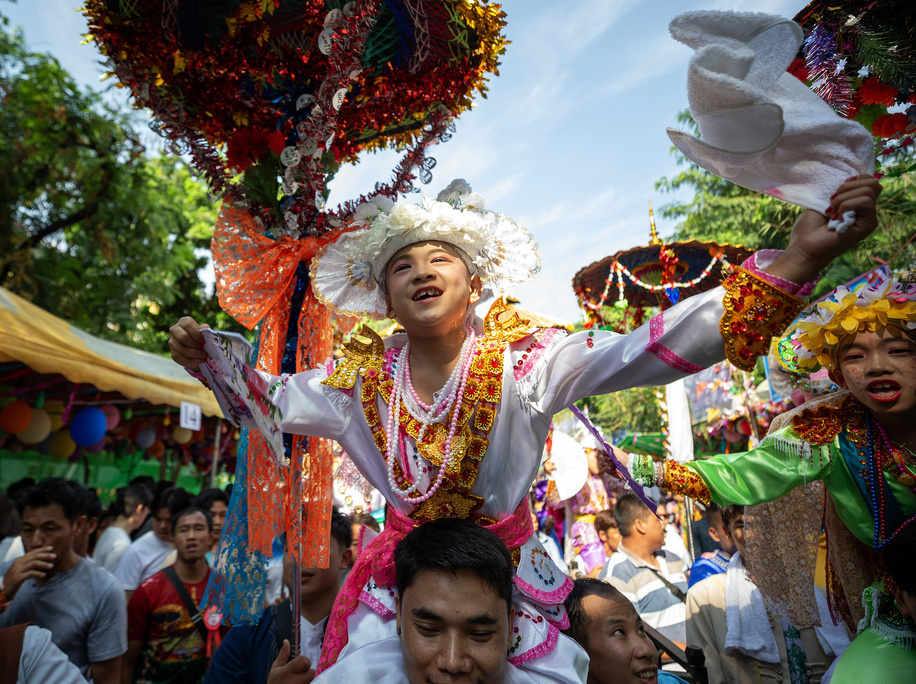 Young ethnic Shan boys dressed in colorful costumes dance while being carried on the shoulders of their family members during an annual Poy Sang Long procession, a traditional rite of passage for boys to be initiated as Buddhist novices at Wat Ku Tao Temple. Poy Sang Long is a Buddhist novice ordination ceremony, of the Thai Yai tribal people, but unlike any other ceremony of its type in the country. Young boys aged between 7 and 14 are ordained as novices to learn Buddhist doctrines.