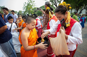 A Thai Woman wearing traditional costumes offers food to novice during the 728th anniversary celebrations of Chiang Mai city. The city of Chiang Mai was founded by The three kings: King Mangrai, King Ngam Mueang and King Ram Khamhaeng on 12 April 1296.