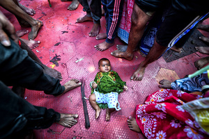 A little baby lies on the floor among the crowd during the annual Gajan Festival's ritual. Gajan is a Hindu festival celebrated mostly in the rural part of West Bengal. The festival is related to Lord Shiva and as per Mythology on the last day of Bengali Calendar (Middle of April) devotees used to worship dead bodies to satisfy Lord Shiva for better rain and harvest. The central theme of this festival is deriving satisfaction through non-sexual pain, devotion and sacrifice.