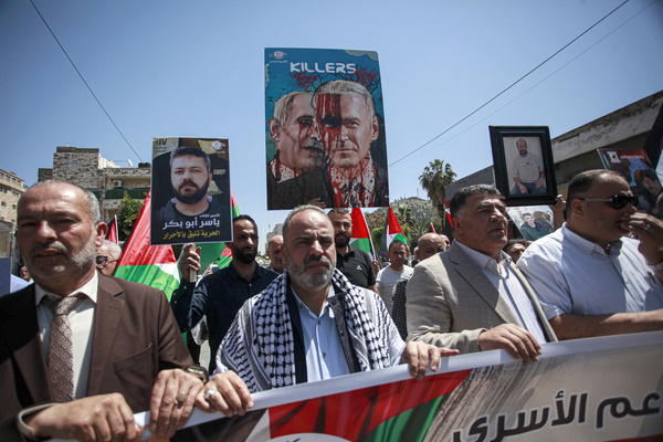 Palestinians hold a banner and placards during a protest against the massacres committed by Israeli forces in Gaza City.