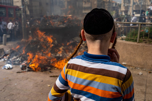 A Jewish boy stands next to the fire pit burning the leaven during the Biur Chametz. During the Biur Chametz, religious Jews fulfill their obligation to inspect their homes for any leaven and eliminate it before the night of Passover. In ultra-Orthodox cities in Israel, fires are set up in major locations in the city for this purpose, where people bring their bread leftovers to burn the leaven. During the seven days of Passover, they are prohibited from eating or possessing any leaven, symbolizing the dough the Israelites did not have time to allow to rise before the Exodus from Egypt. Biur Chametz, also known as 'the burning of the leavened goods,' is a Jewish ceremonial ritual involving the burning of leavened foods (chamets) to mark the start of Passover.
