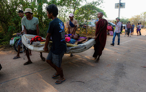 Men and a novice monk are seen carrying a sick elderly man as they flee from the Myawaddy War to Mae Sot. On April 12, Karen KNLA and PDF forces raided the army's 275th military garrison in Myawady town, prompting more than 100 soldiers to attempt to flee to Thailand across Friendship Bridge No. 2. The KNLA/PDF joint forces subsequently attacked these soldiers on the night of April 19th. According to residents, the military council's air response included no fewer than 40 bombs being dropped. As a result of the fighting, approximately 2,000 people fled to Mae Sot, Thailand, across the Moei (Thaung Yin) River.