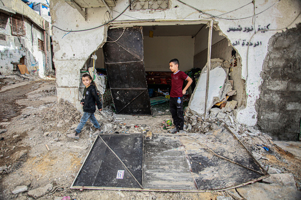 Palestinians walk between rubble following a deadly raid by Israeli forces that commenced Thursday night in the Nur Shams refugee camp near the West Bank town of Tulkarem.