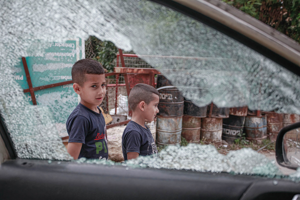 Palestinians kids walk past a destroyed vehicle in an operation by Israeli army forces in Balata refugee camp in the city of Nablus in the West Bank, in which a wanted person by Israeli forces was arrested.