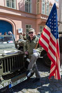 A history enthusiast dressed in the World War II US Army uniform is holding an American flag during the Convoy of Liberty event in Prague. The Convoy of Liberty commemorates the liberation of the western part of the Czech Republic from Nazi occupation by the US Army, as well as the 79th anniversary of the end of World War II in 1945. Throughout the convoy, individual military history clubs and army forces re-enactors join the routes of Allied armies.