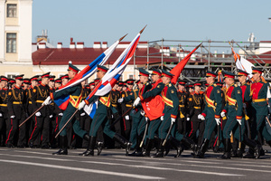 Russian military personnel with flags during a rehearsal for the May 9 Victory Parade on Palace Square pass against the background of the arch of the main headquarters.