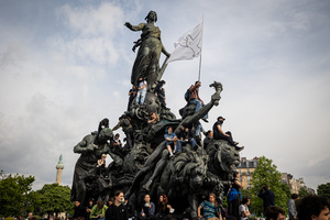 Protesters climb up the monument in Place de la Nation as one holds a flag with a bird of peace during the labour day demonstrations. A day full of clashes between the black-block, anarchists and anti-capitalists groups, with the police became the norm on the celebration of the 1st of May - Labour day in Paris, as demonstrators complaining about president Macron's government and his political and social law changes.