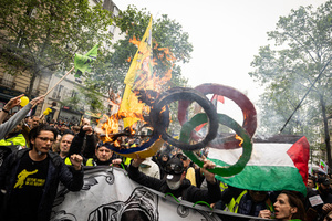 Protestors hold the the olympic games logo as it goes up in flames during the labour day demonstration. A day full of clashes between the black-block, anarchists and anti-capitalists groups, with the police became the norm on the celebration of the 1st of May - Labour day in Paris, as demonstrators complaining about president Macron's government and his political and social law changes.