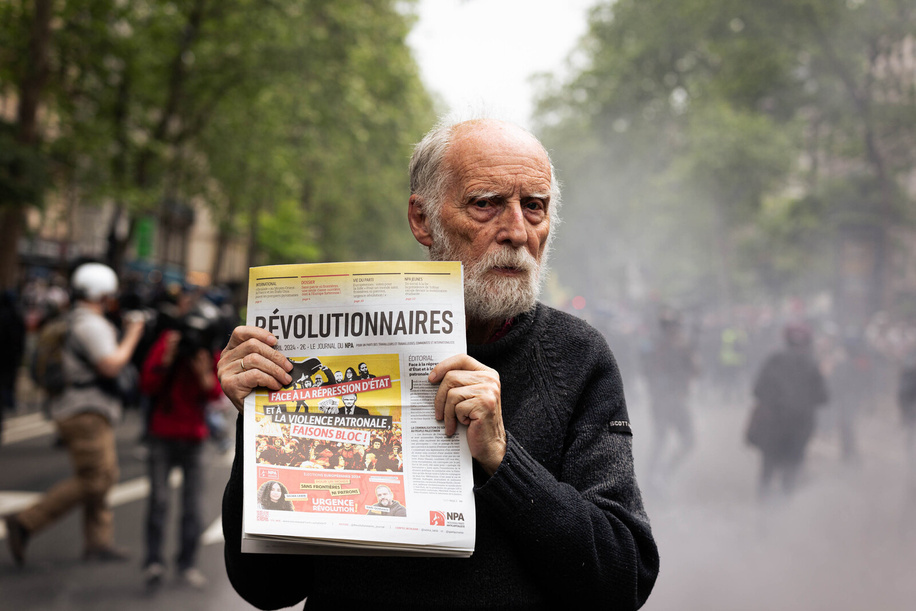 An elderly man shows a newspaper that says 