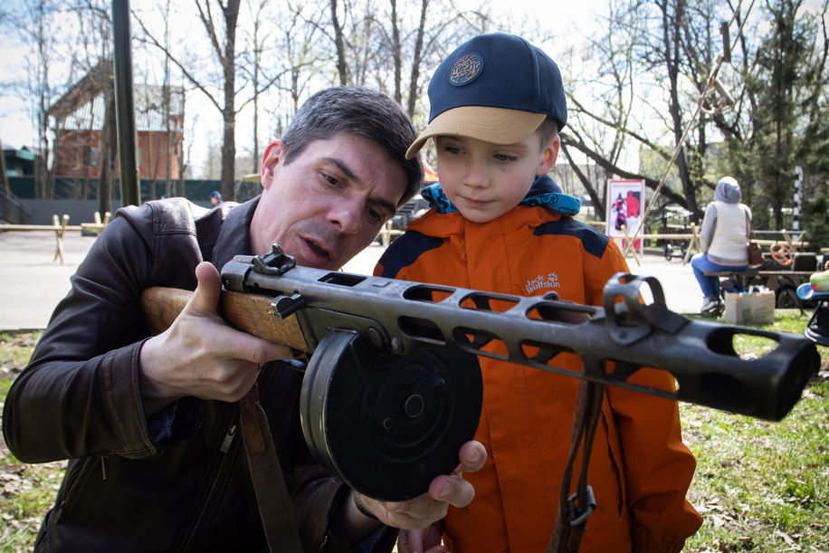 A father shows his son how to properly hold a Shpagin submachine gun during the military festival. The Intra-city Municipal Formation organization of the city Aleksandrovskaya hosted a military festival event titled 