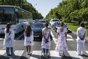 Ukrainian activists covered with fake blood walk at a crossing trying to slow down the traffic and the car of Russia's ambassador near the cemetery to Red Army soldiers. On Russia's "Victory Day" in Warsaw Russia's Ambassador to Poland, Sergey Andreev and his delegation laid a wreath at the monument at the cemetery to Red Army soldiers who died during World War II. During the ceremony Ukrainian activists tried to disturb the event. May 9th, known as "Victory Day" in Russia, is a holiday commemorating the Soviet victory over Nazi Germany in 1945.