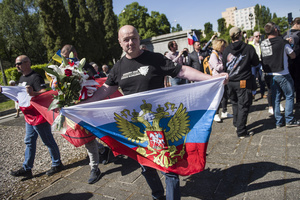 A Russia's supporter holds the Russian Federation's flag at the cemetery to Red Army soldiers. On Russia's "Victory Day" in Warsaw Russia's Ambassador to Poland, Sergey Andreev and his delegation laid a wreath at the monument at the cemetery to Red Army soldiers who died during World War II. During the ceremony Ukrainian activists tried to disturb the event. May 9th, known as "Victory Day" in Russia, is a holiday commemorating the Soviet victory over Nazi Germany in 1945.