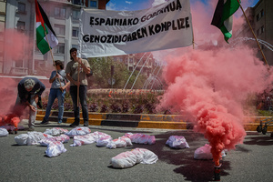 Performance of red flare and sheets on the ground stained with blood, simulating children murdered during the war in the Gaza Strip. Thousands of people participated in a demonstration through the streets of Pamplona calling for a free Palestine.
