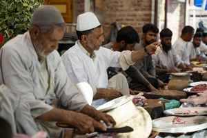 Traditional Kashmiri chefs cut lamb meat to prepare wazwan dishes in Srinagar. Wazwan (Kashmiri: وازِوان) is a traditional multi-course meal in Kashmiri cuisine, renowned as an art form and a cultural emblem. Predominantly meat-based, it features lamb and chicken, with a few vegetarian meals. It is prepared by master chefs called vaste waze, and the meal is typically served during weddings and reunions. Guests share the meal from a large copper platter (traem), they begin with rice and various meat types, including seekh kababs, methi korma, tabak maaz, safed kokur, and zafran kokur. Essential dishes include rista, rogan josh, daniwal korma, aab gosh, marchhwangan korma, and gushtaba, and they conclude with desserts. And its popularity has extended internationally to food festivals and cultural events.