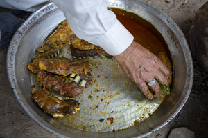 A traditional Kashmiri chef prepares a copper platter (trami) with rice and lamb ribs (tabak maaz) dish in Srinagar. Wazwan (Kashmiri: وازِوان) is a traditional multi-course meal in Kashmiri cuisine, renowned as an art form and a cultural emblem. Predominantly meat-based, it features lamb and chicken, with a few vegetarian meals. It is prepared by master chefs called vaste waze, and the meal is typically served during weddings and reunions. Guests share the meal from a large copper platter (traem), they begin with rice and various meat types, including seekh kababs, methi korma, tabak maaz, safed kokur, and zafran kokur. Essential dishes include rista, rogan josh, daniwal korma, aab gosh, marchhwangan korma, and gushtaba, and they conclude with desserts. And its popularity has extended internationally to food festivals and cultural events.