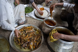 A traditional Kashmiri chef prepares a copper platter (trami) with rice and lamb ribs (tabak maaz) dish in Srinagar. Wazwan (Kashmiri: وازِوان) is a traditional multi-course meal in Kashmiri cuisine, renowned as an art form and a cultural emblem. Predominantly meat-based, it features lamb and chicken, with a few vegetarian dishes. It is prepared by master chefs called vaste waze, and the meal is typically served during weddings and reunions. Guests share the meal from a large copper platter (traem), they begin with rice and various meat types, including seekh kababs, methi korma, tabak maaz, safed kokur, and zafran kokur. Essential dishes include rista, rogan josh, daniwal korma, aab gosh, marchhwangan korma, and gushtaba, and they conclude with desserts. And its popularity has extended internationally to food festivals and cultural events.