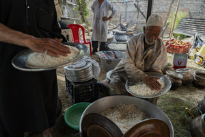 A traditional Kashmiri chef prepares a copper platter (trami) with rice and wazwan dishes in Srinagar. Wazwan (Kashmiri: وازِوان) is a traditional multi-course meal in Kashmiri cuisine, renowned as an art form and a cultural emblem. Predominantly meat-based, it features lamb and chicken, with a few vegetarian dishes. It is prepared by master chefs called vaste waze, and the meal is typically served during weddings and reunions. Guests share the meal from a large copper platter (traem), they begin with rice and various meat types, including seekh kababs, methi korma, tabak maaz, safed kokur, and zafran kokur. Essential dishes include rista, rogan josh, daniwal korma, aab gosh, marchhwangan korma, and gushtaba, and they conclude with desserts. And its popularity has extended internationally to food festivals and cultural events.