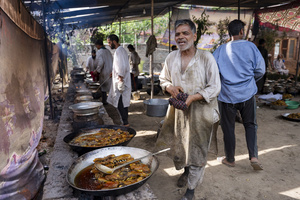 A Kashmiri Traditional Chef reacts as he prepare traditional wazwan dishes in Srinagar. Wazwan (Kashmiri: وازِوان) is a traditional multi-course meal in Kashmiri cuisine, renowned as an art form and a cultural emblem. Predominantly meat-based, it features lamb and chicken, with a few vegetarian meals. It is prepared by master chefs called vaste waze, and the meal is typically served during weddings and reunions. Guests share the meal from a large copper platter (traem), they begin with rice and various meat types, including seekh kababs, methi korma, tabak maaz, safed kokur, and zafran kokur. Essential dishes include rista, rogan josh, daniwal korma, aab gosh, marchhwangan korma, and gushtaba, and they conclude with desserts. And its popularity has extended internationally to food festivals and cultural events.