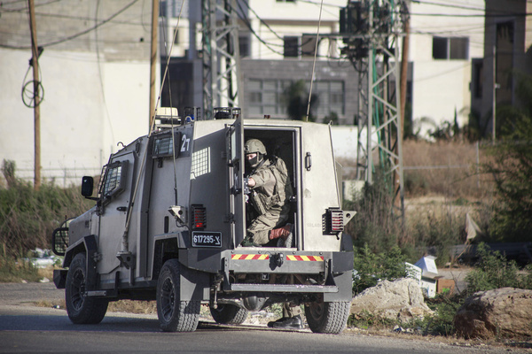 An Israeli soldier seen in the back of the military guarding next to their military vehicle at the entrance to the city of Jenin, during a raid on the city of Jenin and its camp in the northern occupied West Bank.