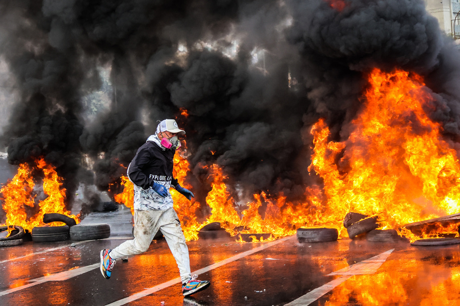 A fisherman runs past a barricade of tires and flames of fire during a demonstration in defense of fishing quotas. Artisanal fishermen in Caleta Portales, Valparaíso Region, mobilized to defend fishing quotas and oppose the resumption of squid trawling.