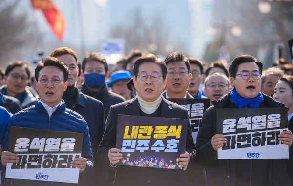 South Korea's main opposition Democratic Party (DP) leader Lee Jae-myung (C) and his party members march with "Dismiss Yoon Suk Yeol." placards during a rally calling for impeached South Korean President Yoon Suk Yeol's dismissal at the National Assembly. South Korea's Police on March 18 sent bodyguards to protect opposition leader Lee Jae-myung amid threats to assassinate him. The police protection began March 18 for an undetermined period of time after Lee's Democratic Party (DP) requested it, citing concerning text messages received by several of its lawmakers. The messages reportedly warned against a plot to assassinate Lee with a smuggled Russian-made pistol. Police did not disclose the number of bodyguards assigned to Lee or other specifics of the security detail.