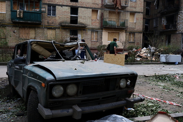 A man carries plywood behind a damaged car near a residential building that was heavily damaged by Russian missile strikes amid the Russian invasion of Ukraine. In the early morning of June 17, the Russian army attacked the Ukrainian capital with missiles and Shahed-type combat drones, resulting in destruction and damages to residential buildings in different parts of the city. At least 28 people were killed and 140 were injured in Kyiv. For the second day in a row, rescuers cleared up rubbles of destroyed buildings and searched for dead bodies.